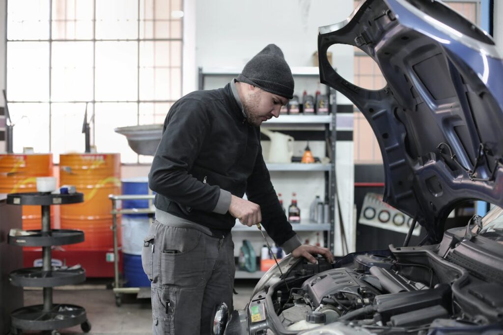 Mechanic checking a car engine in a garage, ensuring quality maintenance and repair.