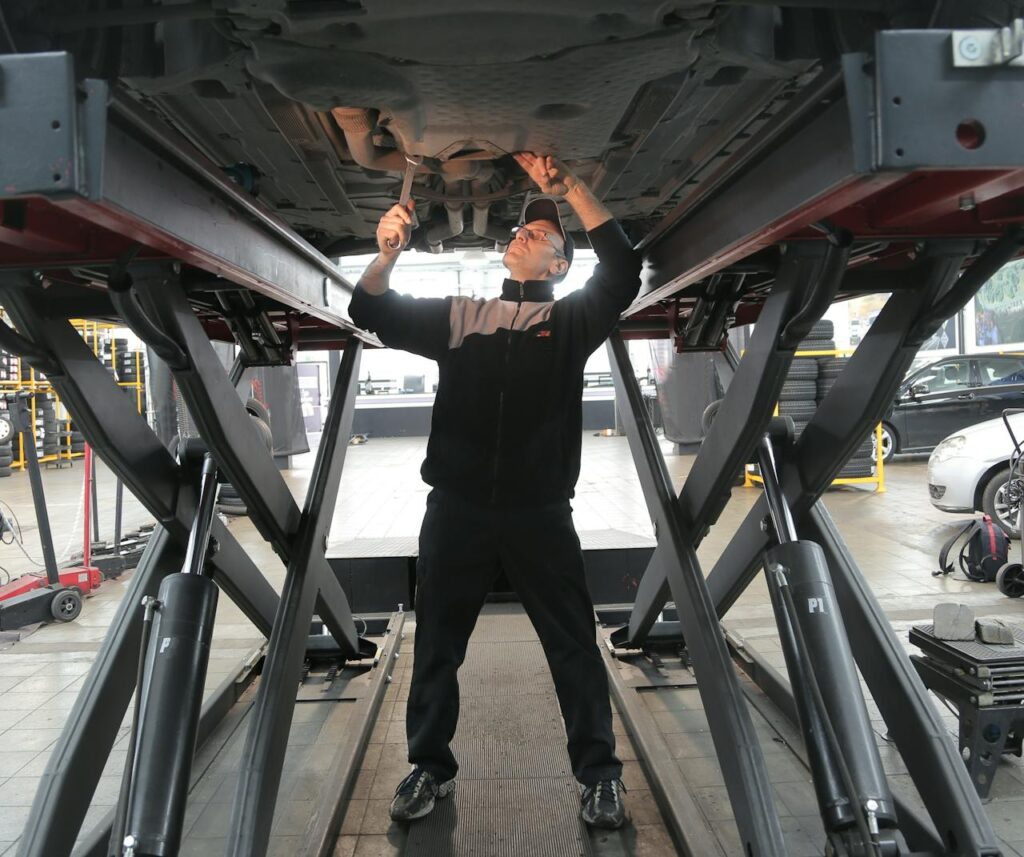 Mechanic inspecting and repairing a vehicle in a professional auto garage.