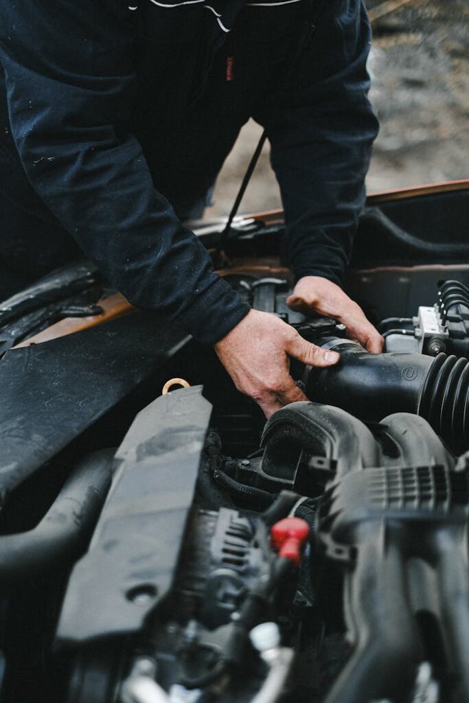 Close-up of a mechanic's hands working on a car engine inside a workshop.